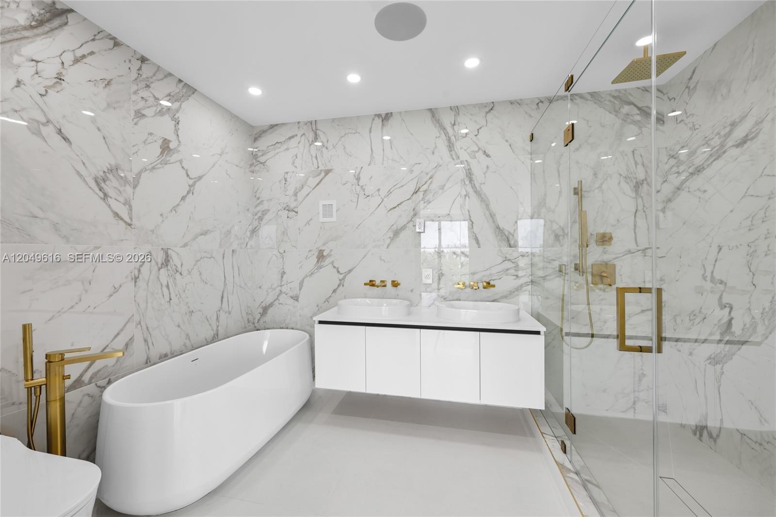 A modern bathroom features a white soaking tub, double vanity, and glass-enclosed shower with marble — 3220 NE 7th St, Pompano Beach FL 33062, POMPANO BEACH, FL