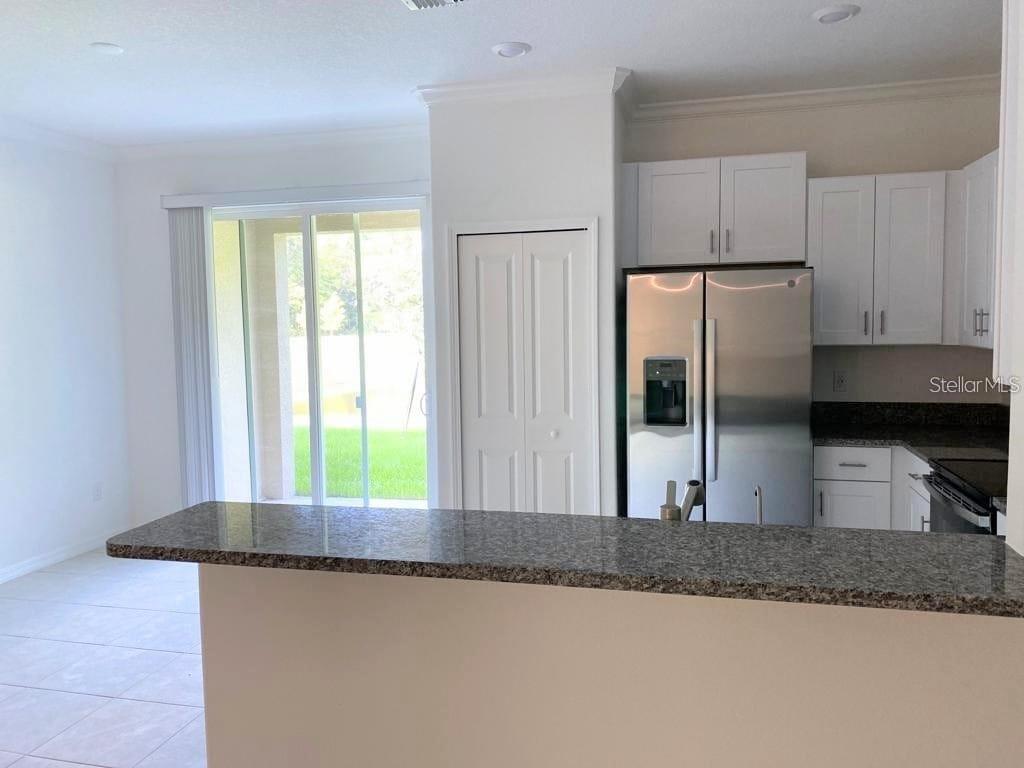 A kitchen features white cabinets, stainless steel appliances, and a granite-topped breakfast bar — 17478 NECTAR FLUME DRIVE, LAND O LAKES, FL