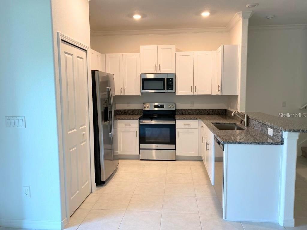 A kitchen with white cabinets, stainless steel appliances, and granite countertops — 17478 NECTAR FLUME DRIVE, LAND O LAKES, FL