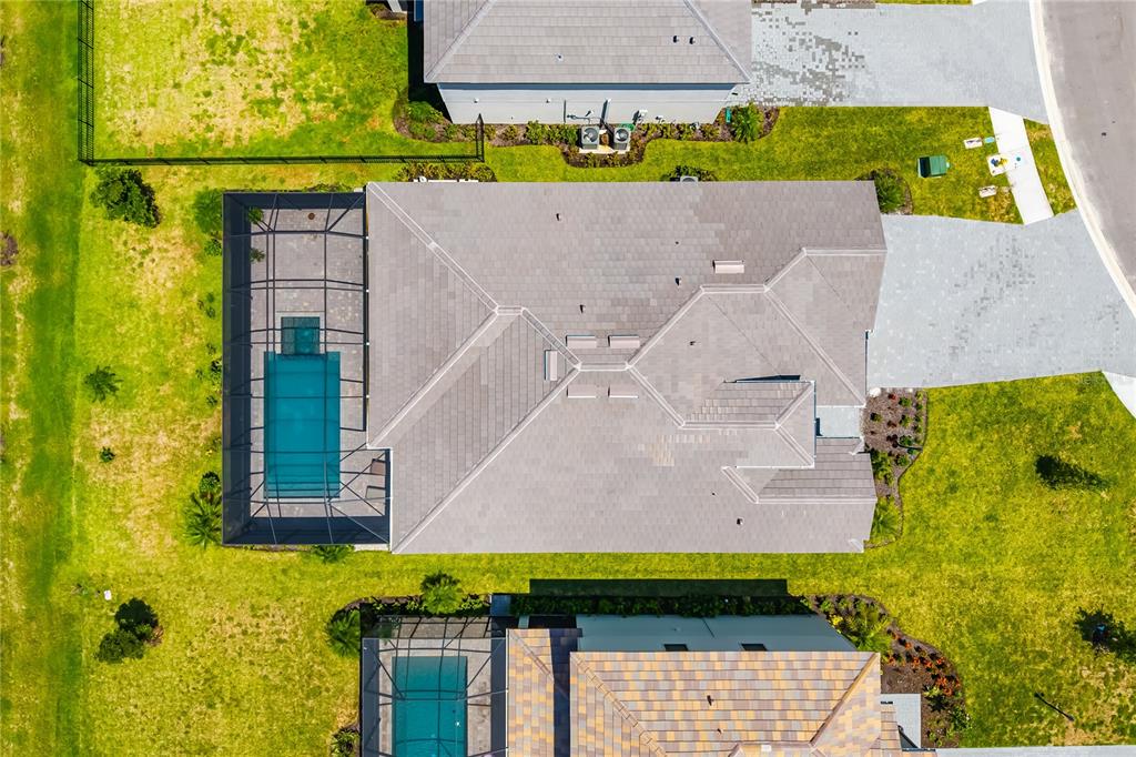 An aerial view shows a house with a tiled roof, a screened-in pool, and landscaping — 5030 SARATOGA SPRINGS RUN, BRADENTON, FL