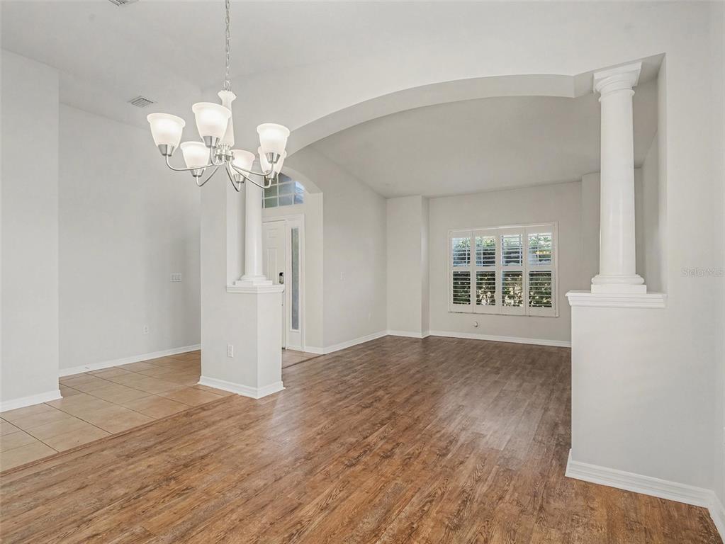 A dining area with wood-look flooring, a chandelier, and a white columned archway — 11409 FLORA SPRINGS DRIVE, RIVERVIEW, FL