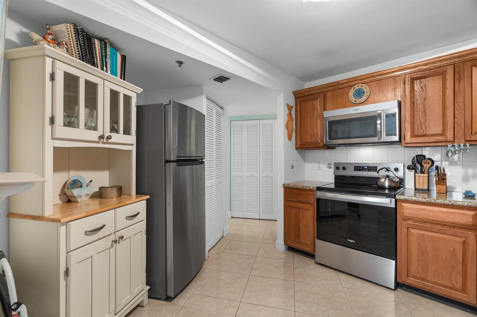 A kitchen features wood cabinets, stainless steel appliances, a white hutch, and tile flooring — 1361 S Ocean Boulevard # 303, Pompano Beach FL 33062, POMPANO BEACH, FL