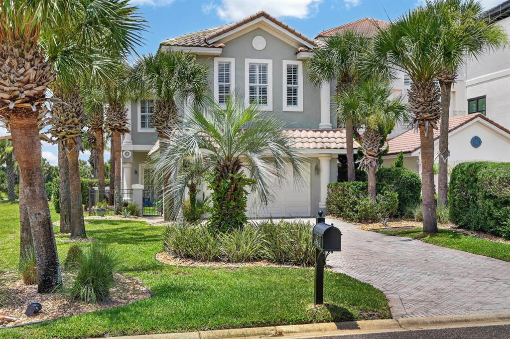 A two-story gray house with a tiled roof, palm trees, and a brick driveway — 32 NORTHSHORE AVENUE, PALM COAST, FL