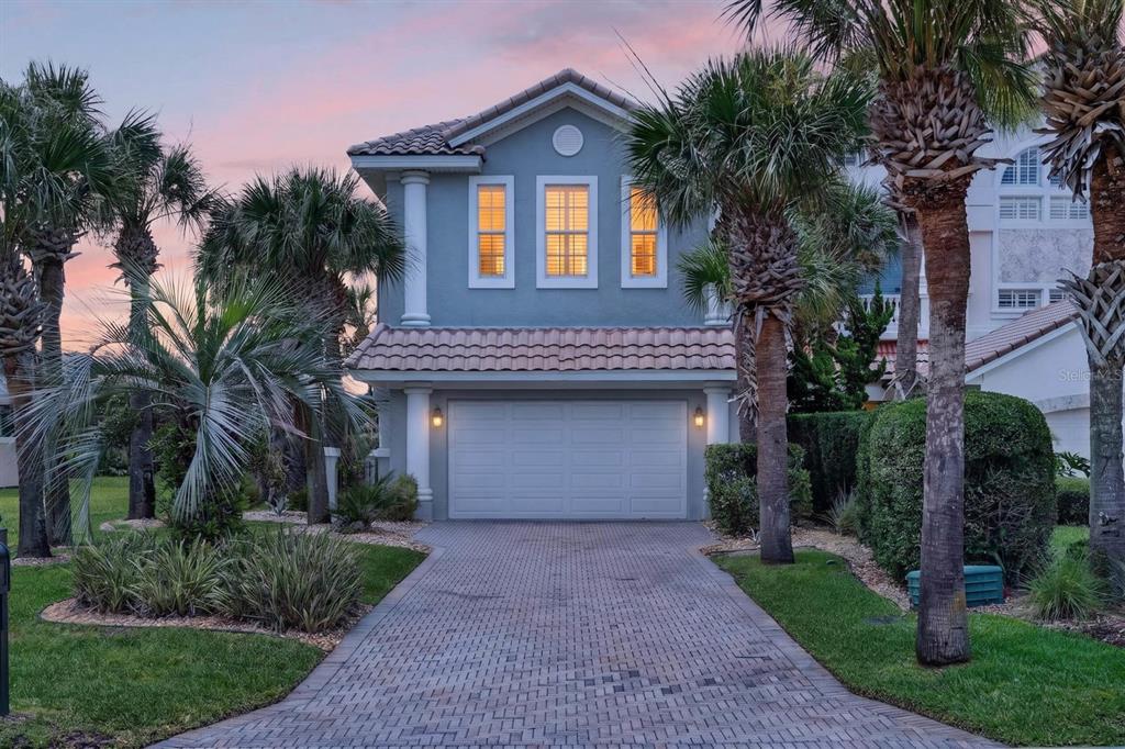 A two-story blue house with a paved driveway and palm trees at dusk — 32 NORTHSHORE AVENUE, PALM COAST, FL