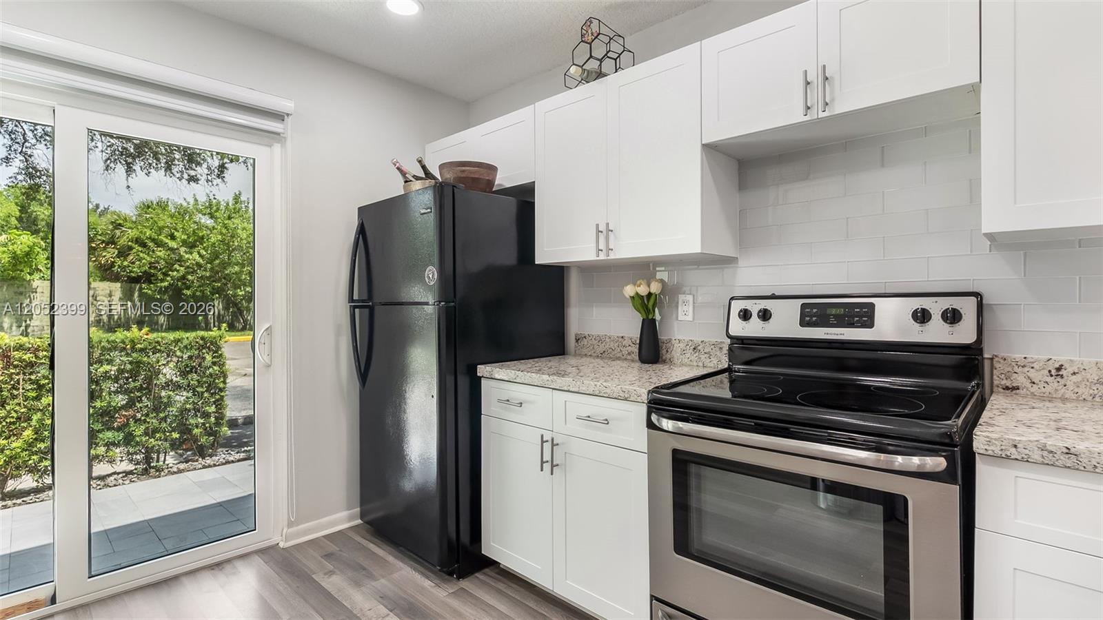A kitchen features white cabinets, granite countertops, a black refrigerator, and a stainless steel stove — 785 Crystal Lake Dr # 785, Deerfield Beach FL 33064, DEERFIELD BEACH, FL