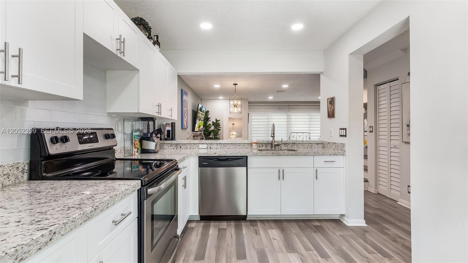 A kitchen features white cabinets, granite countertops, stainless steel appliances, and wood-look flooring — 785 Crystal Lake Dr # 785, Deerfield Beach FL 33064, DEERFIELD BEACH, FL