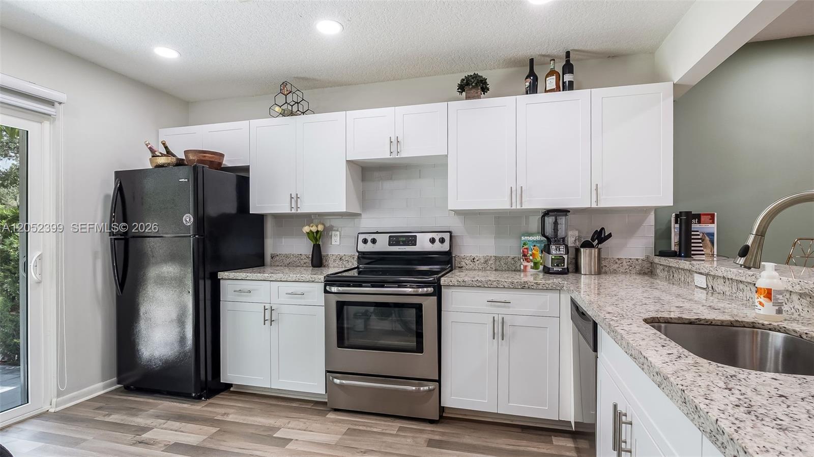 A kitchen features white cabinets, granite countertops, stainless steel appliances, and a black refrigerator — 785 Crystal Lake Dr # 785, Deerfield Beach FL 33064, DEERFIELD BEACH, FL