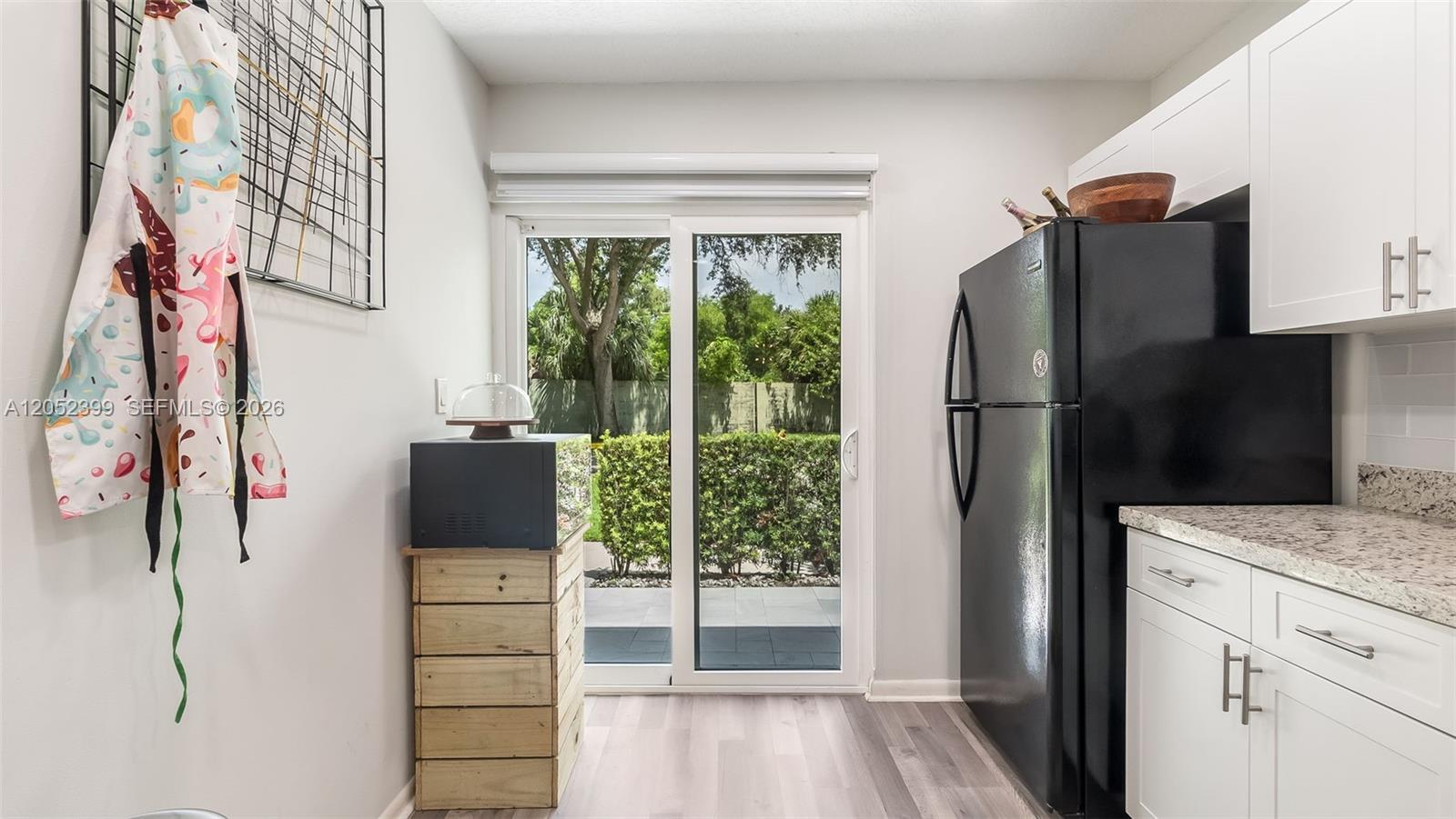 A kitchen features white cabinets, a black refrigerator, and a sliding glass door to outdoors — 785 Crystal Lake Dr # 785, Deerfield Beach FL 33064, DEERFIELD BEACH, FL