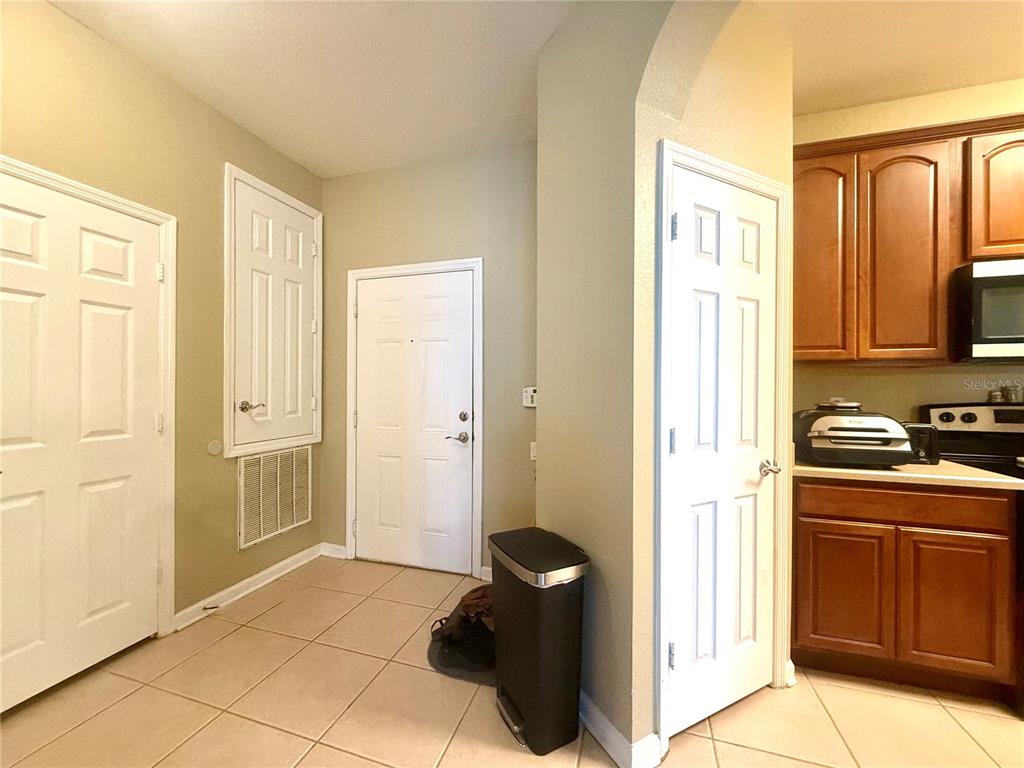 A kitchen area with tile flooring, a white entry door, and wooden cabinets — 3314 ROBERT TRENT JONES DRIVE UNIT 410, ORLANDO, FL