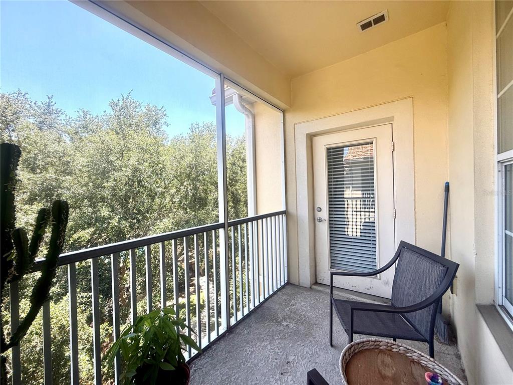 A screened-in balcony features a metal railing, a glass door, and a single outdoor chair — 3314 ROBERT TRENT JONES DRIVE UNIT 410, ORLANDO, FL