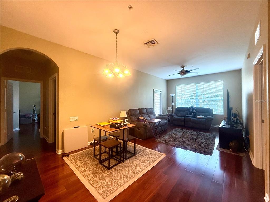 A living room and dining area with hardwood floors, a ceiling fan, and a chandelier — 3314 ROBERT TRENT JONES DRIVE UNIT 410, ORLANDO, FL