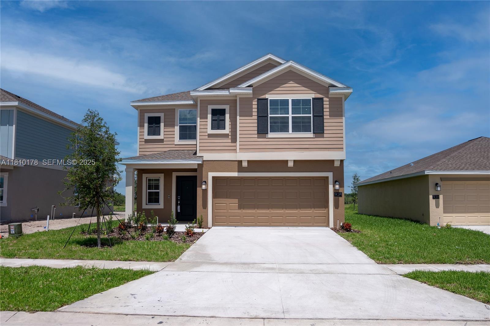 A two-story house with tan siding, a brown garage door, and a concrete driveway — 934 CATTLEMAN STREET, Winter Haven FL 33884, WINTER HAVEN, FL