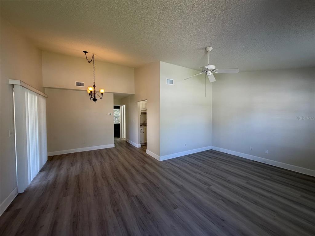 An open-concept living and dining area features vaulted ceilings, light walls, and wood-look flooring — 14 BIRDIE DRIVE, NEW SMYRNA BEACH, FL