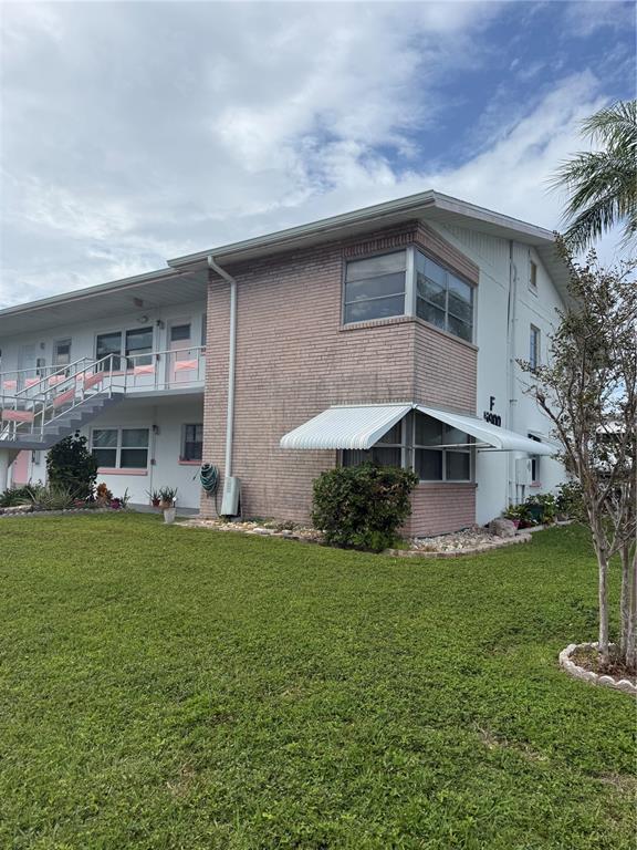 A two-story apartment building features a brick facade, white trim, and a metal awning — 5900 21ST STREET N UNIT 10, ST PETERSBURG, FL
