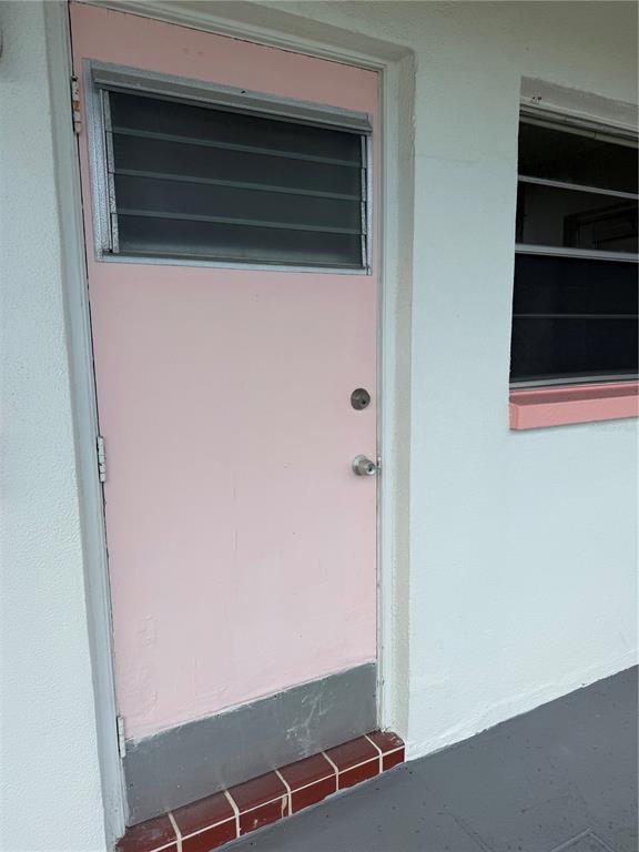 A pink exterior door with a louvered window and metal kickplate sits beside a window — 5900 21ST STREET N UNIT 10, ST PETERSBURG, FL