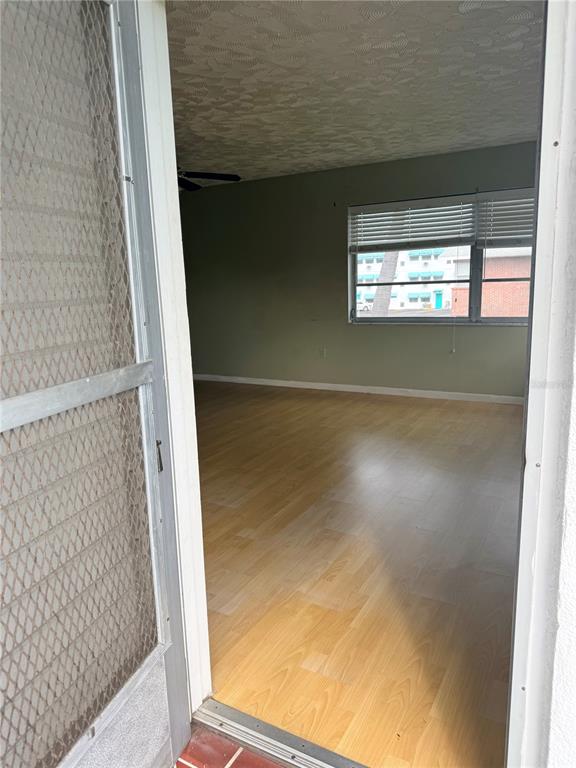 A view through a screen door into an empty room with light wood-look flooring — 5900 21ST STREET N UNIT 10, ST PETERSBURG, FL