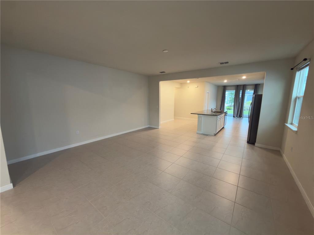 An open-concept living area features light-colored floor tiles and a kitchen island with granite countertops — 6383 TRAILBLAZE BEND, ST CLOUD, FL
