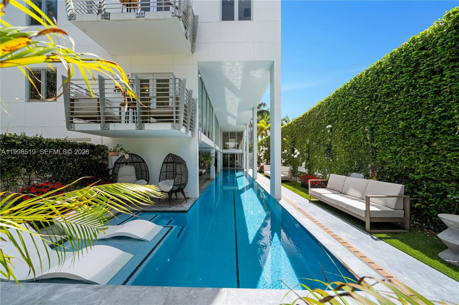 A long, narrow lap pool sits beside a modern white building with a green hedge — 215 Palm Ave, Miami Beach FL 33139, MIAMI BEACH, FL