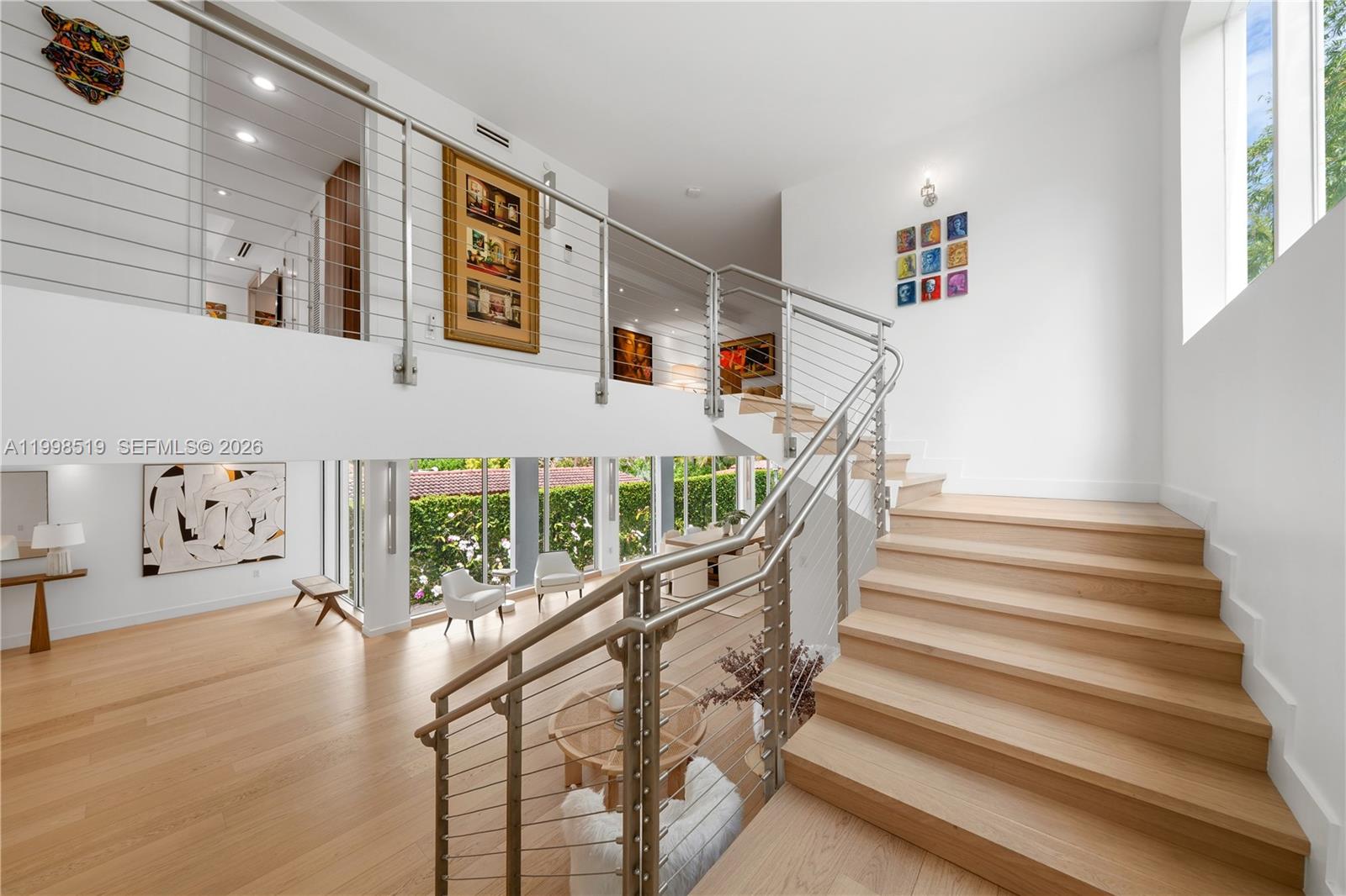 A modern two-story foyer features light wood flooring, a floating staircase, and cable railings — 215 Palm Ave, Miami Beach FL 33139, MIAMI BEACH, FL
