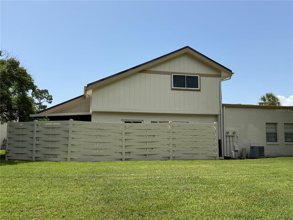 A two-story house exterior features a beige fence, vertical siding, and a grassy lawn — 2617 FOREST RUN COURT, CLEARWATER, FL