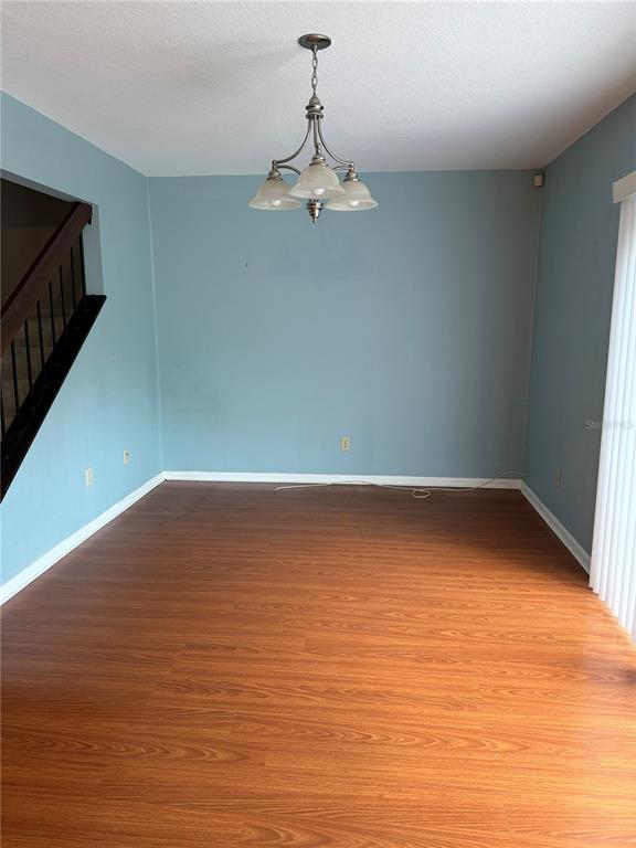 An empty dining room features light blue walls, wood-look flooring, and a central chandelier — 2617 FOREST RUN COURT, CLEARWATER, FL