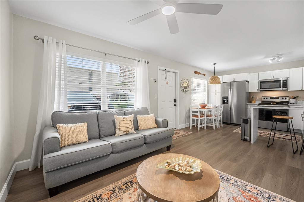 A living room with a grey sofa and a kitchen with white cabinets and appliances — 3724 S ATLANTIC AVENUE UNIT 20, DAYTONA BEACH, FL