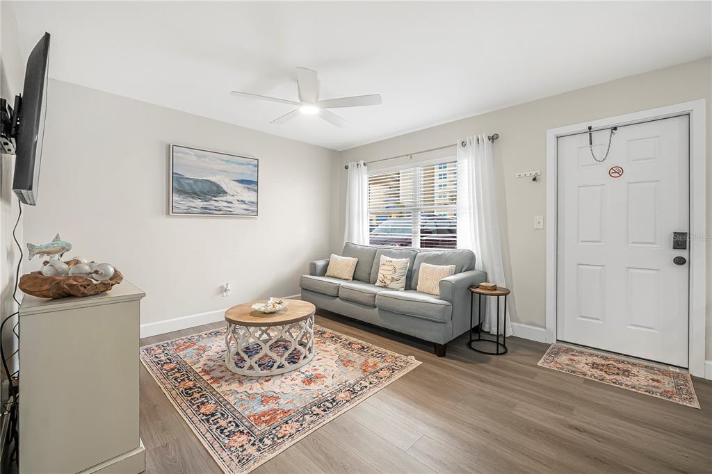 A living room features a gray sofa, a patterned area rug, and a white door — 3724 S ATLANTIC AVENUE UNIT 20, DAYTONA BEACH, FL