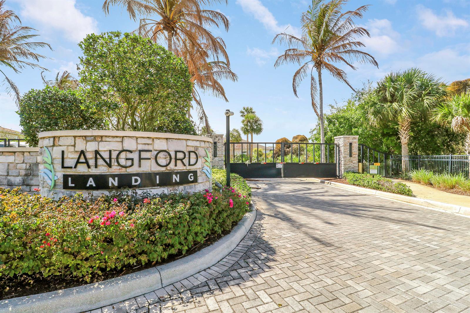 A stone monument sign marks the gated entrance to a residential community with palm trees — 2475 NE Evinrude Circle, Jensen Beach FL 34957, JENSEN BEACH, FL