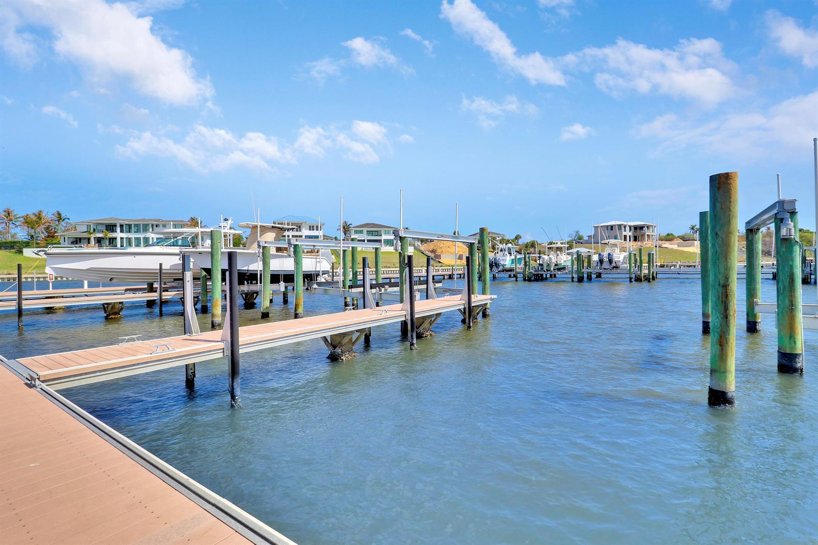 A wooden boat dock extends into a waterway with several boats moored at nearby slips — 2475 NE Evinrude Circle, Jensen Beach FL 34957, JENSEN BEACH, FL
