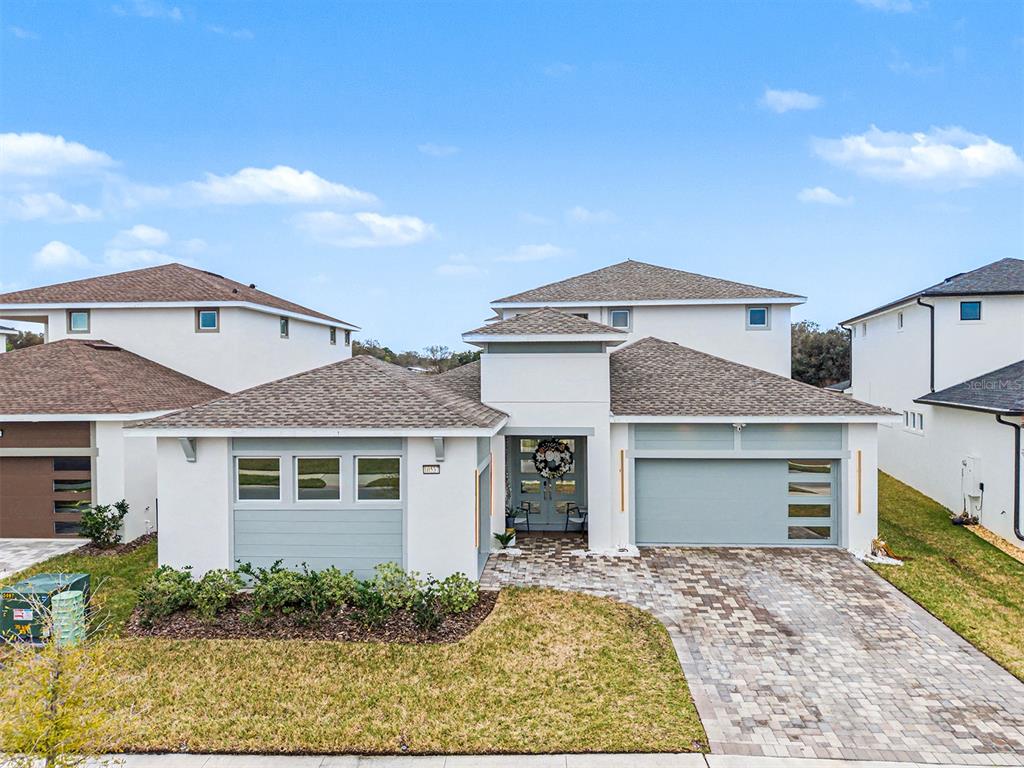A two-story house with a light-colored stucco exterior, a paver driveway, and a two-car garage — 10537 TORCHWOOD SEA WAY, SAN ANTONIO, FL