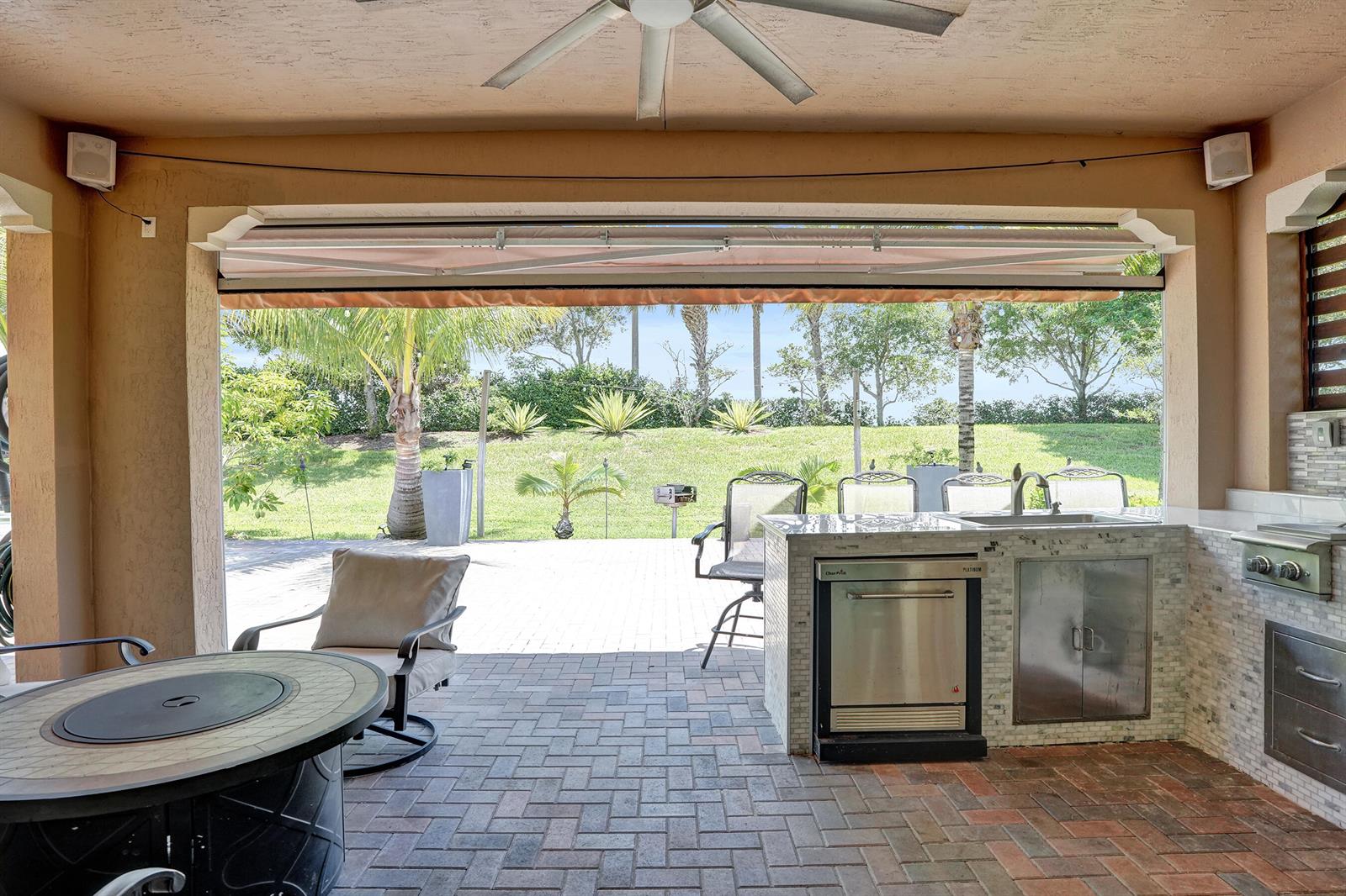 A covered outdoor patio features a kitchen island with a grill, sink, and dining area — 11405 Solstice Circle, Parkland FL 33076, PARKLAND, FL