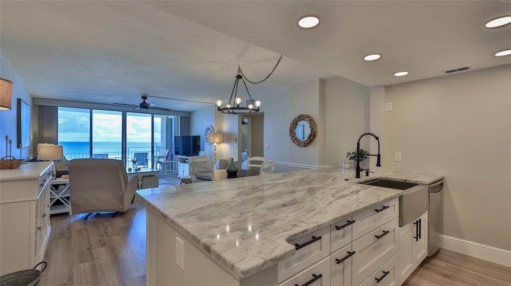 A kitchen island with a marble countertop overlooks a living area with an ocean view — 4495 S ATLANTIC AVENUE UNIT 401, PONCE INLET, FL
