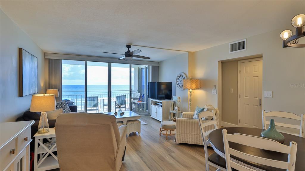 A living and dining area features light wood flooring, a ceiling fan, and ocean views — 4495 S ATLANTIC AVENUE UNIT 401, PONCE INLET, FL