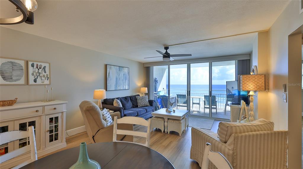 A living room with a blue sofa, beige armchairs, and a balcony overlooking the ocean — 4495 S ATLANTIC AVENUE UNIT 401, PONCE INLET, FL