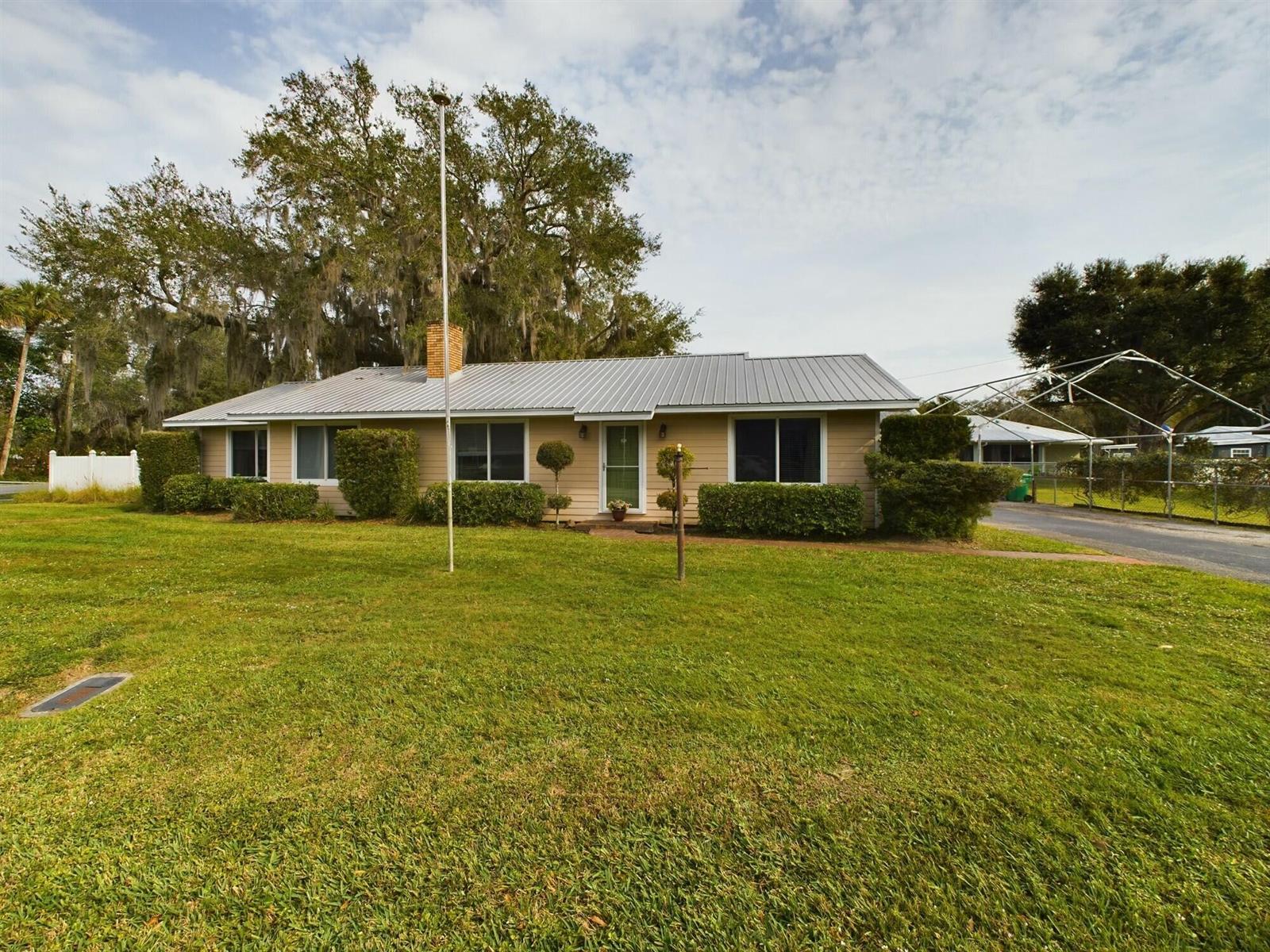 A single-story house with tan siding, a metal roof, and a large front lawn — 1517 SW 7th Avenue, Okeechobee FL 34974, OKEECHOBEE, FL
