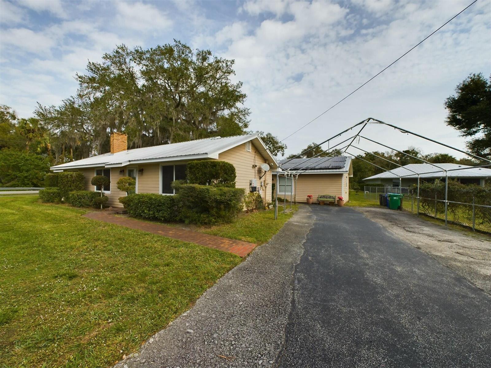 A single-story house with tan siding, a metal roof, and a metal carport over asphalt — 1517 SW 7th Avenue, Okeechobee FL 34974, OKEECHOBEE, FL