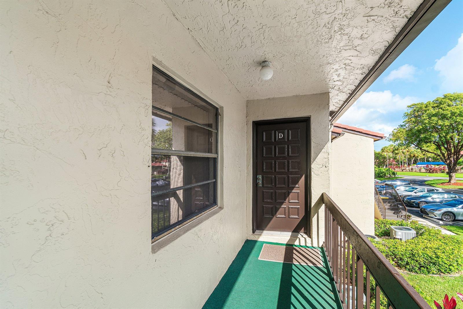 An exterior view of an apartment entrance with a brown door labeled D — 8320 Casa Del Lago # D, Boca Raton FL 33433, BOCA RATON, FL
