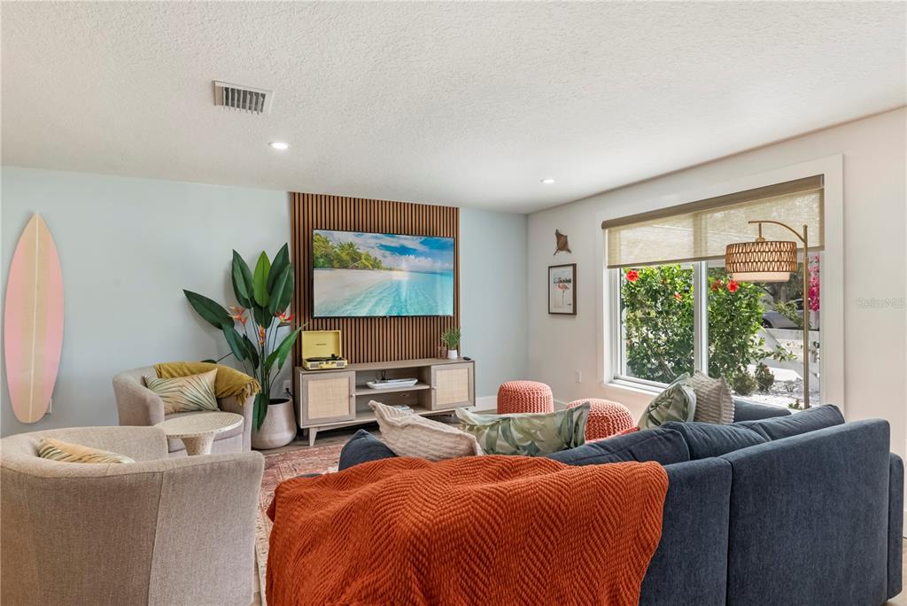 A living room features a slatted wood accent wall, a television, and a blue sofa — 103 W NORTH BRANCH ROAD, RUSKIN, FL
