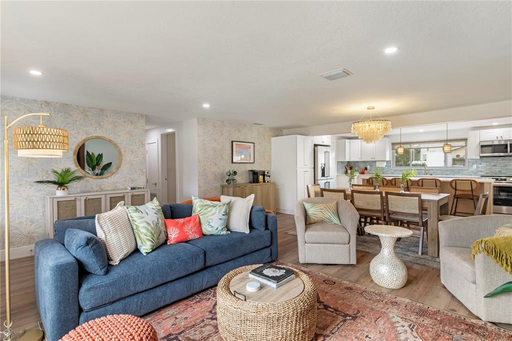 A living room with a blue sofa, patterned rug, and open-concept kitchen and dining area — 103 W NORTH BRANCH ROAD, RUSKIN, FL