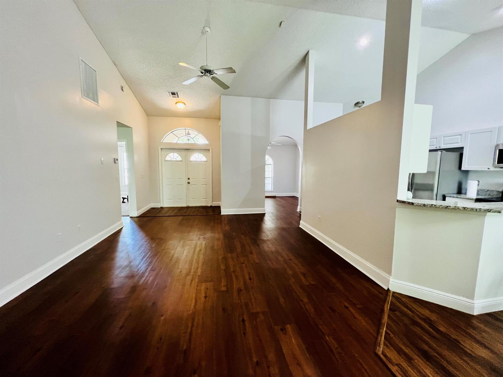 An open-concept living area features dark wood flooring, high ceilings, and a white double-door entrance — 2485 Stonegate Drive, Wellington FL 33414, WELLINGTON, FL