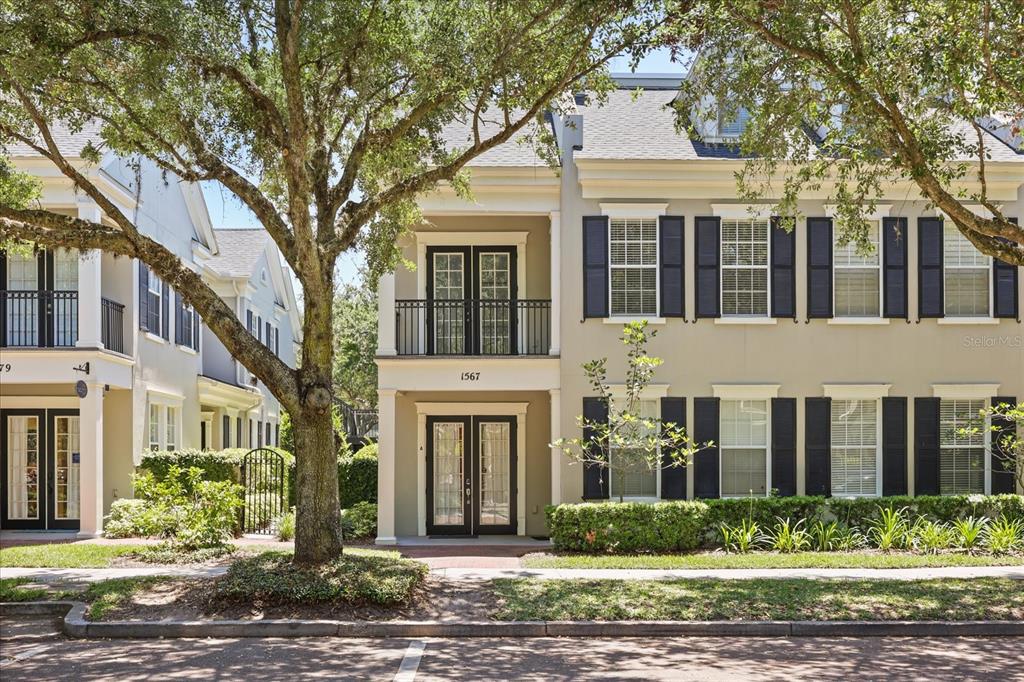 A multi-story townhouse with a balcony, black shutters, and a front entrance under a portico — 1567 LAKE BALDWIN LANE, ORLANDO, FL