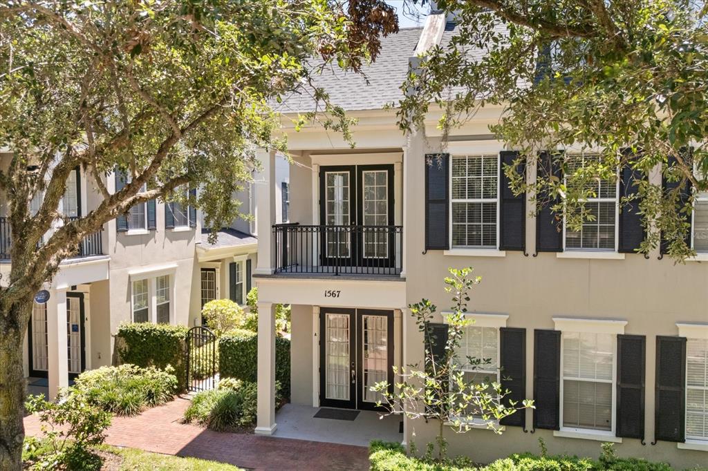 A two-story tan townhouse with black shutters, a balcony, and a brick walkway — 1567 LAKE BALDWIN LANE, ORLANDO, FL