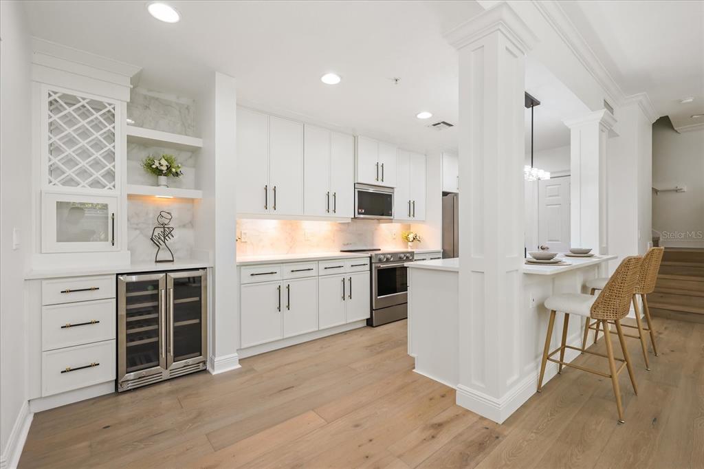 A bright kitchen features white cabinetry, a wine refrigerator, and a breakfast bar with stools — 1567 LAKE BALDWIN LANE, ORLANDO, FL