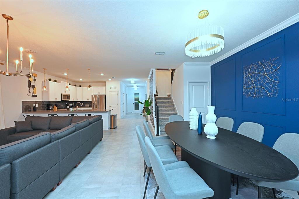 An open-concept living and dining area features a blue accent wall, modern lighting, and tile flooring — 2956 PENELOPE LOOP, KISSIMMEE, FL