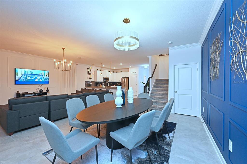 A dining area with an oval table and blue accent wall opens to a kitchen — 2956 PENELOPE LOOP, KISSIMMEE, FL