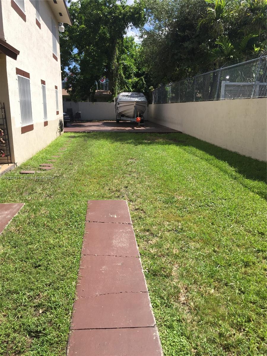 A side yard features a grassy lawn, a concrete walkway, and a boat on a trailer — 160 NW 27th St, Miami FL 33127, MIAMI, FL