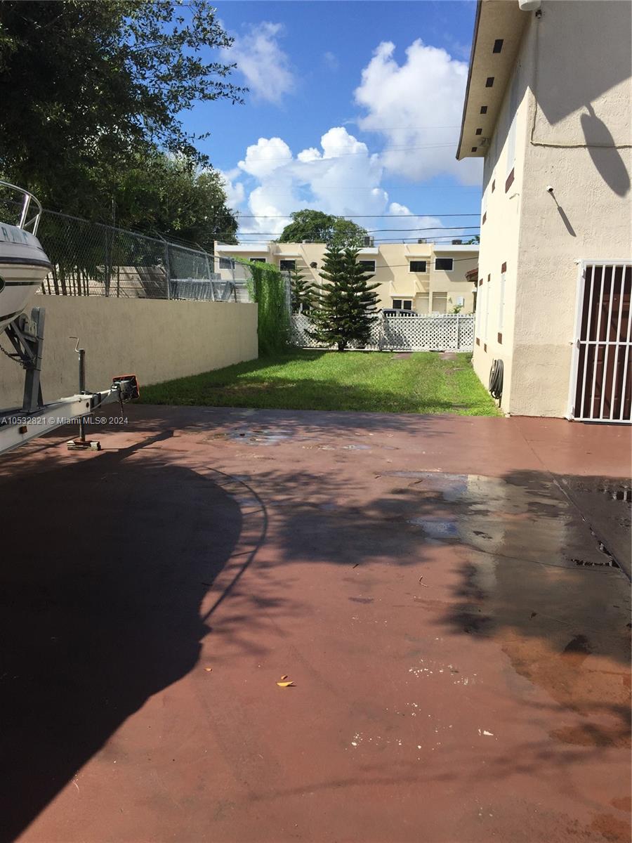 A paved driveway leads to a grassy backyard area next to a multi-story building — 160 NW 27th St, Miami FL 33127, MIAMI, FL