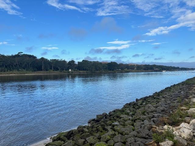 A rocky shoreline borders a calm river with a forested bank under a blue sky — 244 YACHT HARBOR DRIVE, PALM COAST, FL