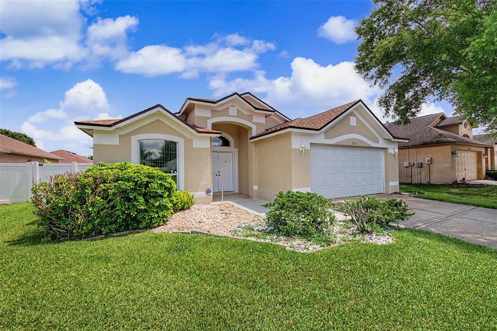 A single-story tan house with a two-car garage and a landscaped front yard — 29641 FOG HOLLOW DRIVE, WESLEY CHAPEL, FL