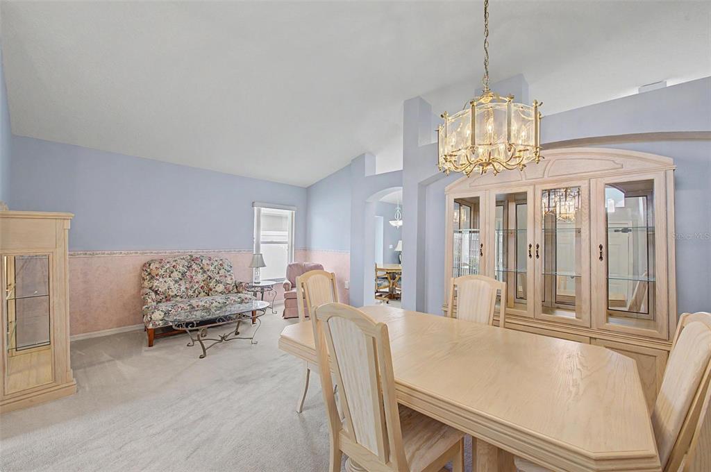 A dining room with a light wood table, matching hutch, and a floral patterned sofa — 29641 FOG HOLLOW DRIVE, WESLEY CHAPEL, FL